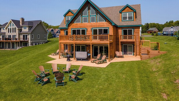 A large wooden house with a balcony, a deck, and outdoor seating. - Lakefront Lodge w/ Hot Tubs, Games & More (Swanton)