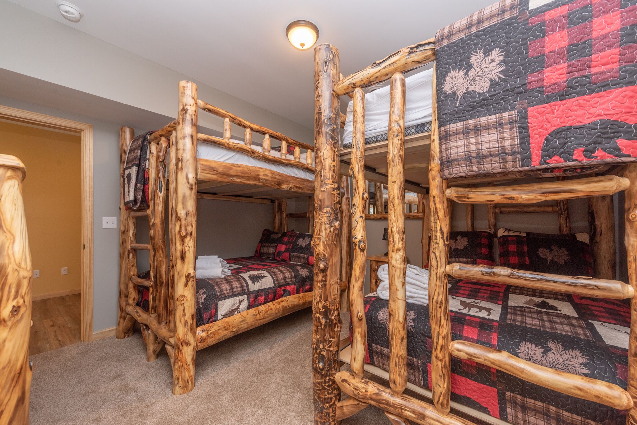 Une chambre rustique avec un lit superposé en bois, dotée d’une tête de lit matelassée et d’une échelle.