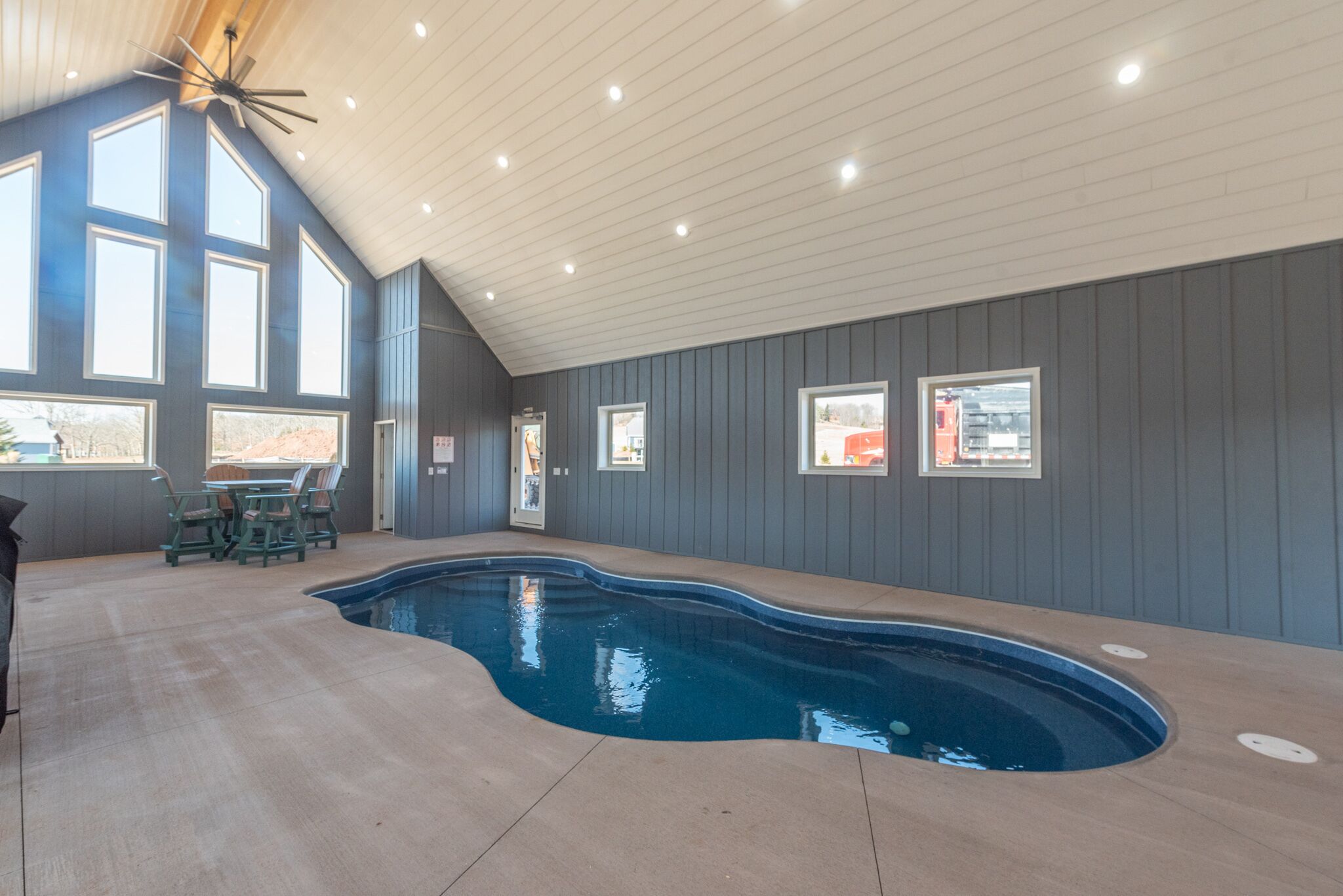 An indoor swimming pool with a sloped ceiling, built-in seating, and large windows.