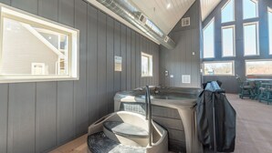 A spa area with a hot tub, a covered seating area, and large windows providing natural light. - Lakefront Lodge w/ Hot Tubs, Games & More (Swanton)