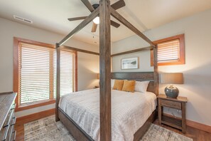 Un dormitorio con cama con dosel, cabecera de madera y mesita de noche con lámpara.