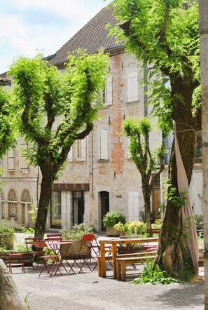 Relax in a serene outdoor space surrounded by mature trees and comfortable seating areas.