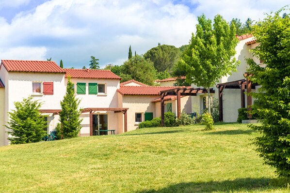 Houses on a gentle slope, surrounded by trees and a lush lawn.