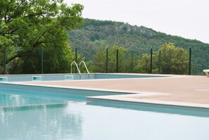 Relax by the pool surrounded by lush greenery and a serene natural landscape.