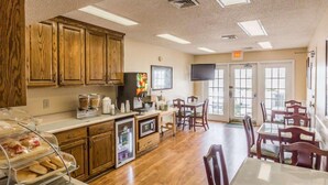 A dining area with wooden cabinets, a refrigerator, a television, and a door leading outside.