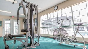 A gym with exercise equipment, a bicycle, and large windows.
