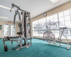 Un gimnasio con equipo de ejercicio, una bicicleta y ventanas amplias.