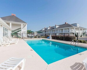 A swimming pool with lounge chairs, a staircase, and a building with multiple windows and balconies. - Rodeway Inn Sylacauga Hwy 280 (Sylacauga)