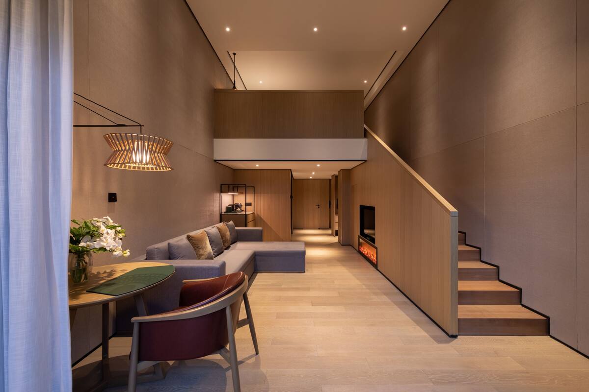 A modern interior with a staircase, a seating area, and a fireplace.