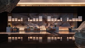A modern reception area with a central counter, seating, and a unique wall design. - Melia Chongqing (Chongqing)