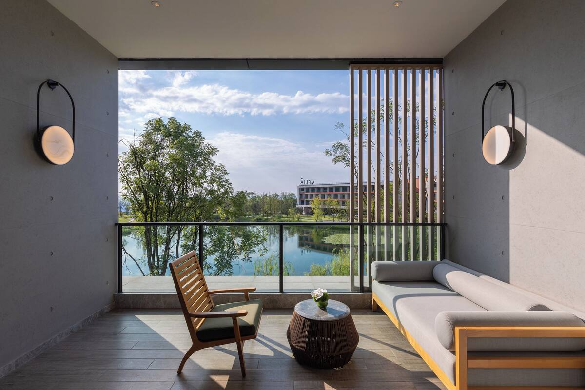 A modern room with a sofa, a wooden chair, and a round table with a vase.