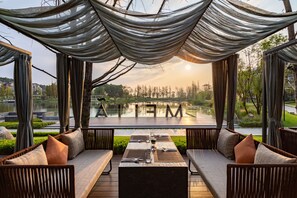 Un espacio al aire libre con mesas preparadas para comer, con vistas a un lago y árboles.