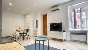 Una sala moderna con sofá, una mesita, televisor y un comedor con sillas y mesa.