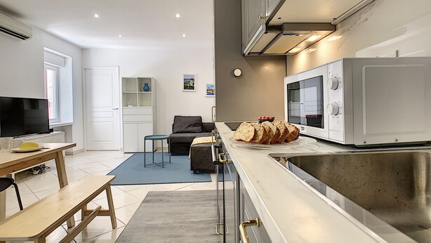Una cocina moderna con microondas, un lavamanos y una zona de comedor con banco y mesa.