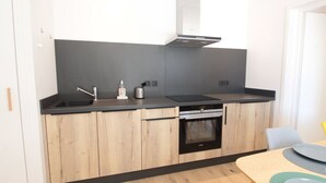 A modern kitchen with a black countertop, wooden cabinets, a built-in oven, and a stainless steel sink.