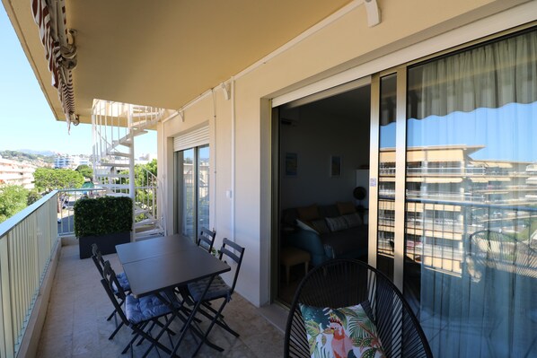 A balcony with a dining table, chairs, and a sofa.