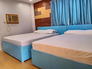 A room with two beds, a wooden headboard, a wall-mounted air conditioner, and blue curtains. - Reddoorz Near Gaisano Grand Cordova (Cordova)