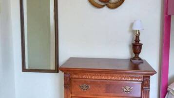 A wooden dresser with drawers and a mirror above it, a decorative wall piece, and a lamp on top of the dresser.