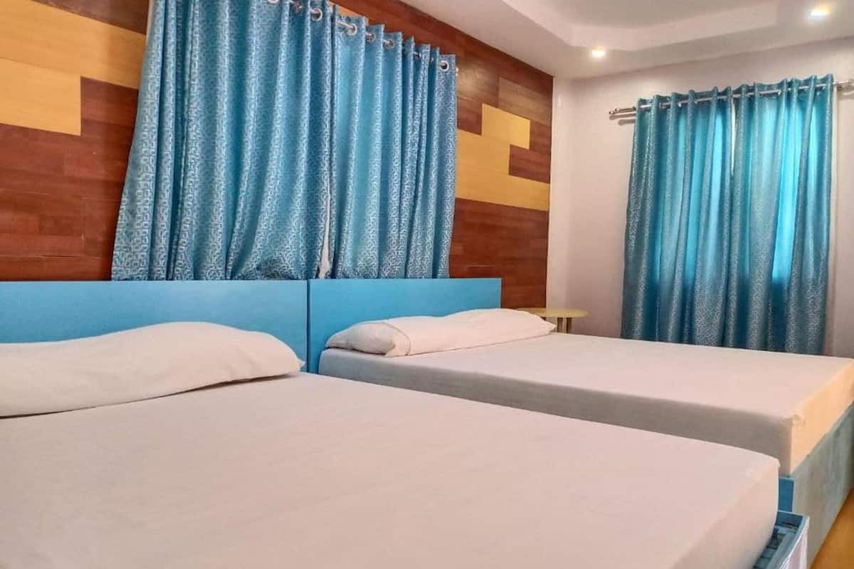 Une chambre d’hôtel avec deux lits, des rideaux bleus et une tête de lit en bois.