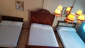 A room with three single beds, a wooden headboard, a painting on the wall, and a chandelier. - Reddoorz Near Gaisano Grand Cordova (Cordova)