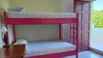 Una cama litera con estructura rosa y ropa de cama blanca, una mesita de noche de madera con una lámpara, y una puerta que da al exterior.