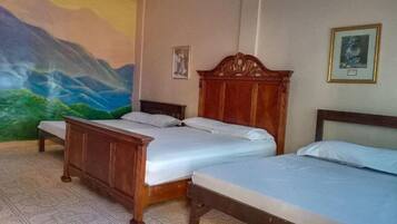 Una camera d'albergo con due letti, un affresco sulla parete e un quadro incorniciato.