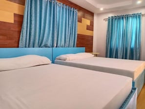 A hotel room with two single beds, a wooden headboard, and blue curtains. - Reddoorz Near Gaisano Grand Cordova (Cordova)