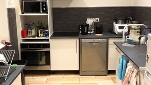 Eine kleine Küche mit Mikrowelle, Backofen, Geschirrspüler und Kaffeemaschine.