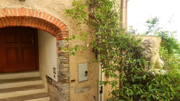 A stone building with a wooden door, a brick archway, and a lion statue. - Fewo für 6 Personen "200 Jahre Altes Pfarrhaus" (Ghiffa)
