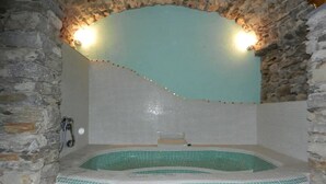 A stone-walled hot tub with a tiled interior, a faucet, and two wall-mounted lights. - Fewo für 6 Personen "200 Jahre Altes Pfarrhaus" (Ghiffa)