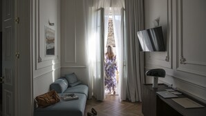 Habitación de hotel con cama, escritorio con computadora, televisor y vista al exterior.