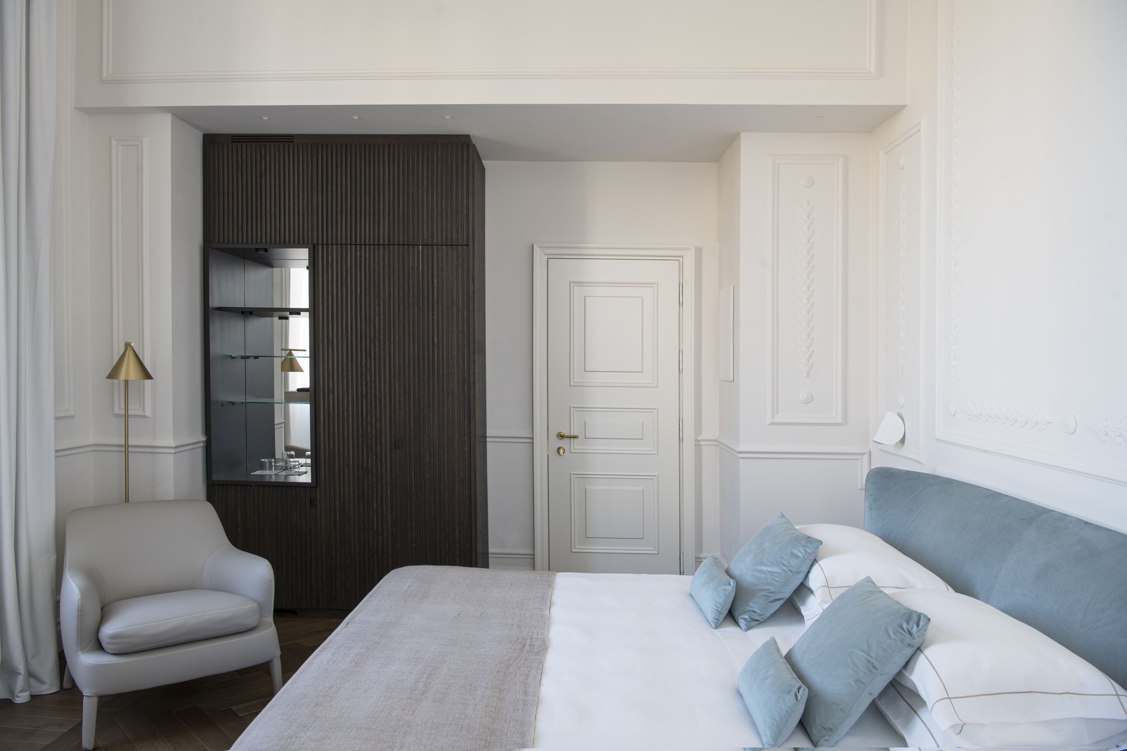 Una camera d'albergo con un letto, una sedia, un armadio e uno specchio.