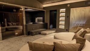 Un dormitorio moderno con una cama curvada, un vestidor amplio y una zona de estar integrada.