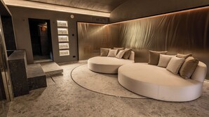 Un interior moderno con un sofá modular curvo, una escalera y una pared con iluminación empotrada.