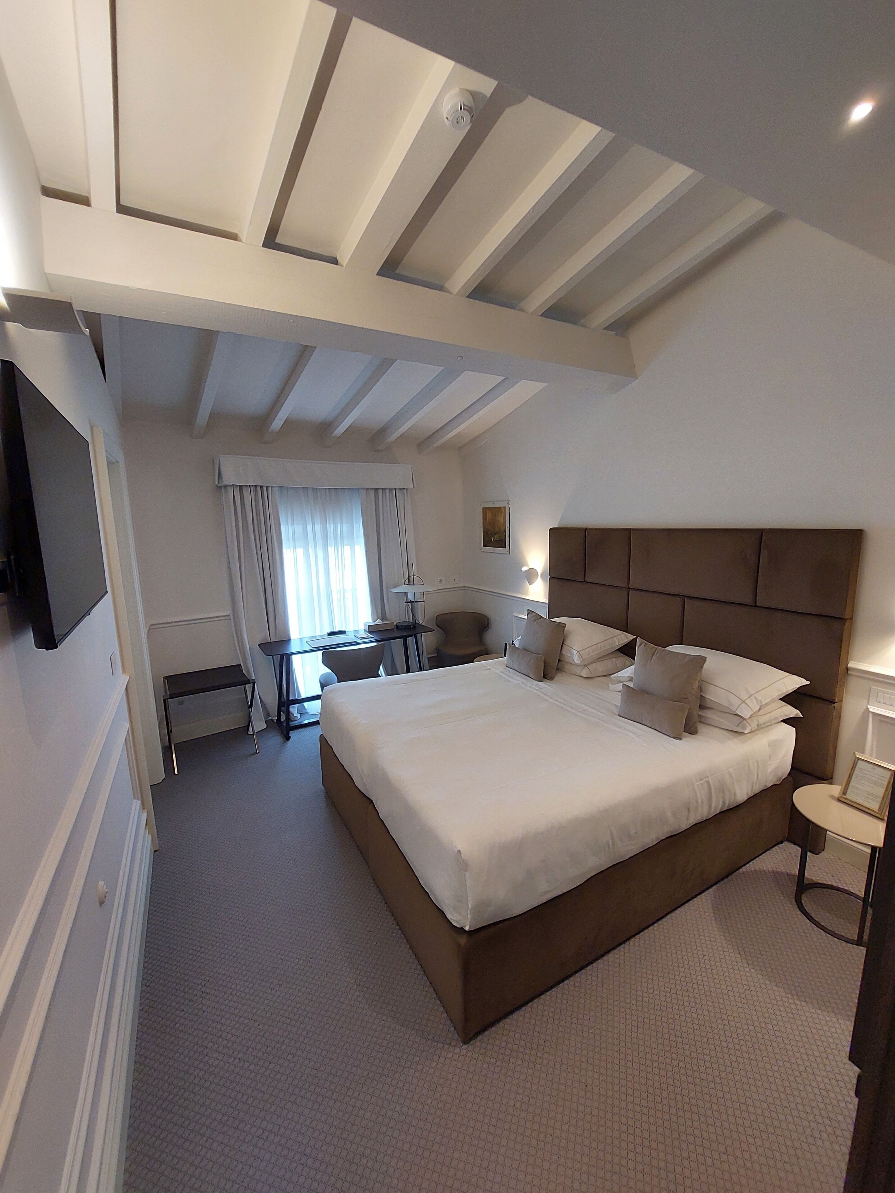 A modern hotel room with a large bed, a desk, and a chair.