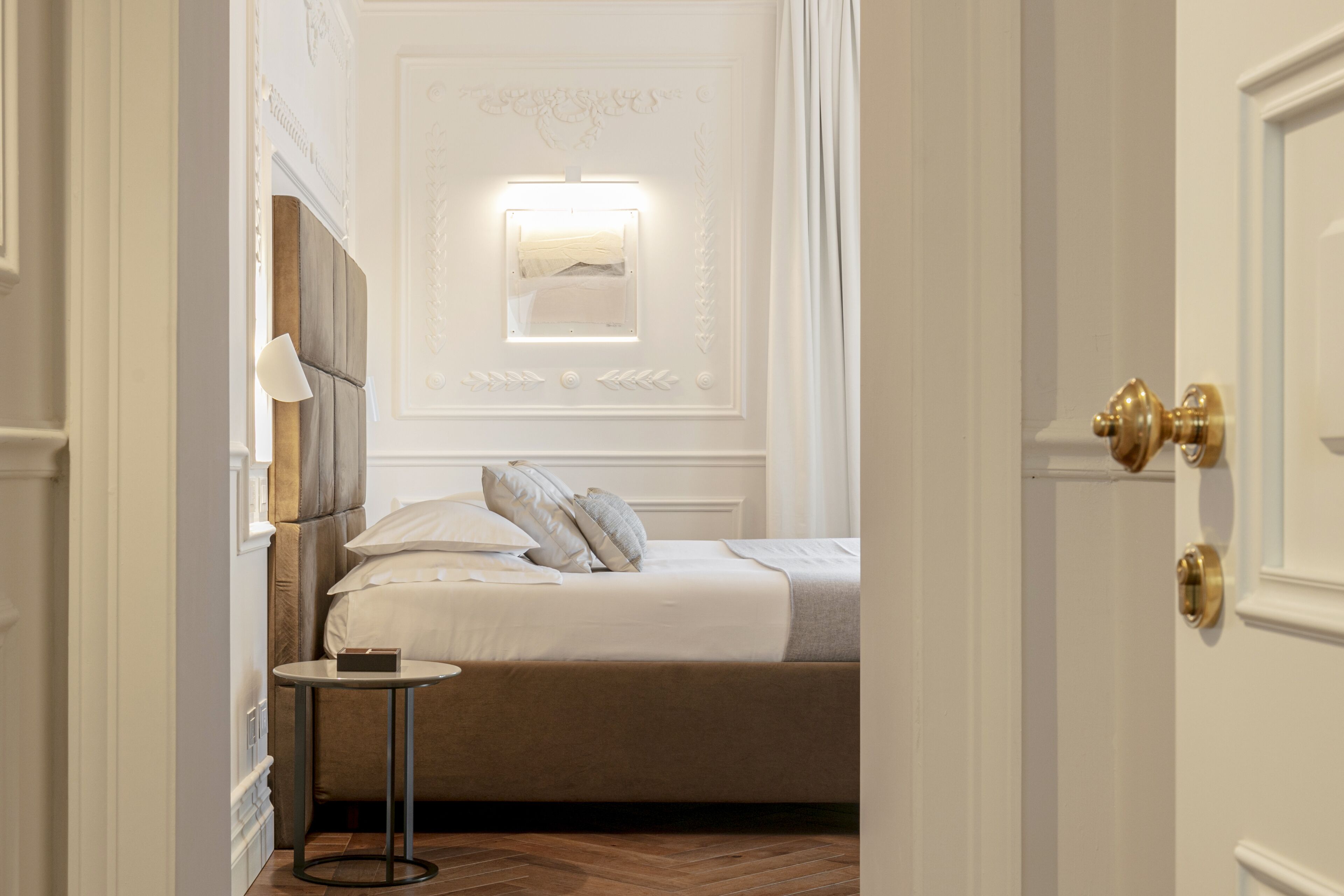 Une chambre à coucher comprenant un lit, une table de chevet et un luminaire fixé au mur.