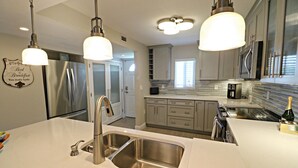 A modern kitchen with stainless steel appliances, a double sink, and pendant lighting. - SABTC 303-Luxury 2 Bedroom/2 Bath Ocean View Condo! (St. Augustine)