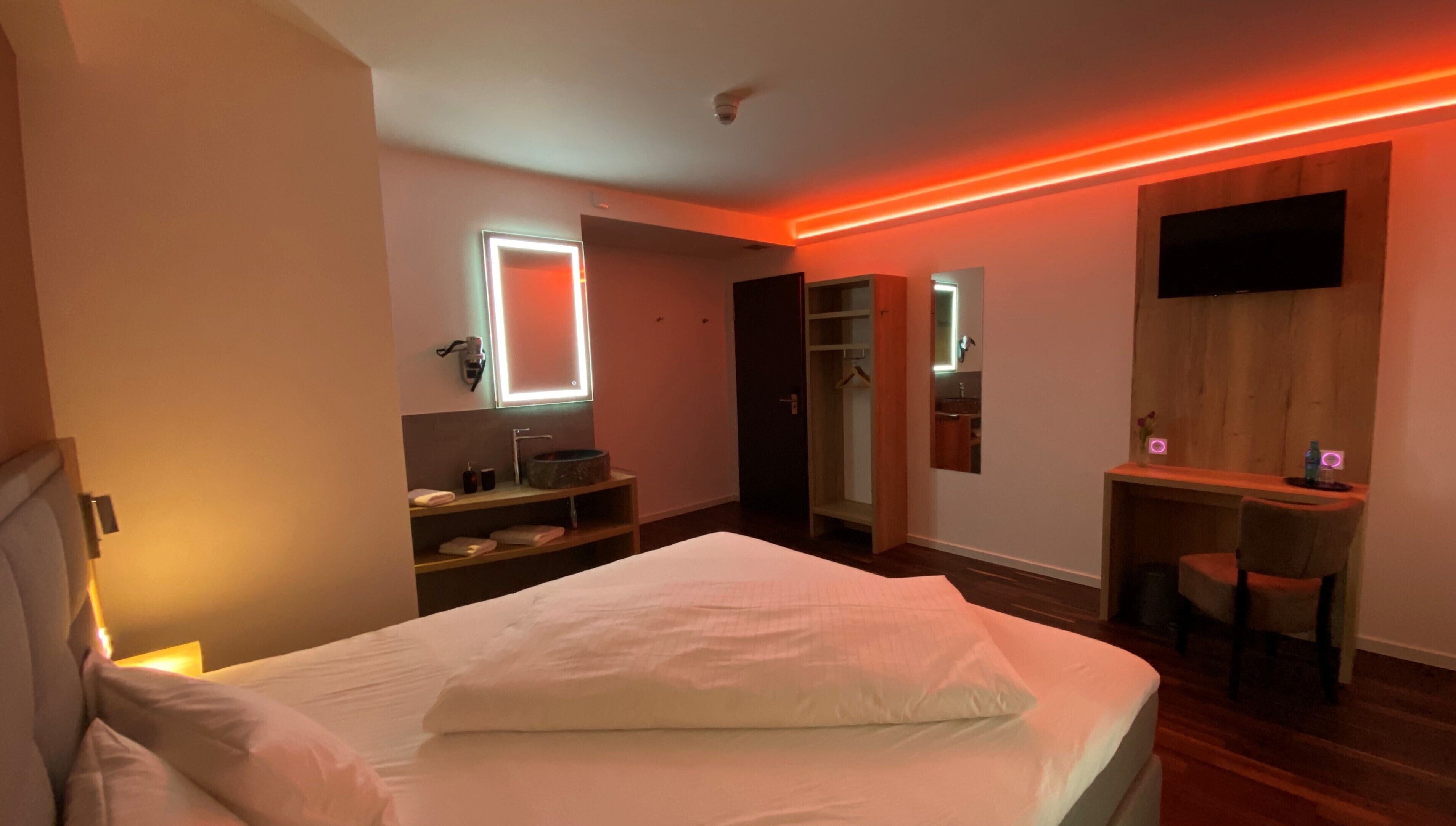 A modern bedroom with a bed, bedside table, and a TV mounted on the wall.