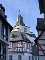Un edificio tradicional con entramado de madera, una torre destacada y un reloj.