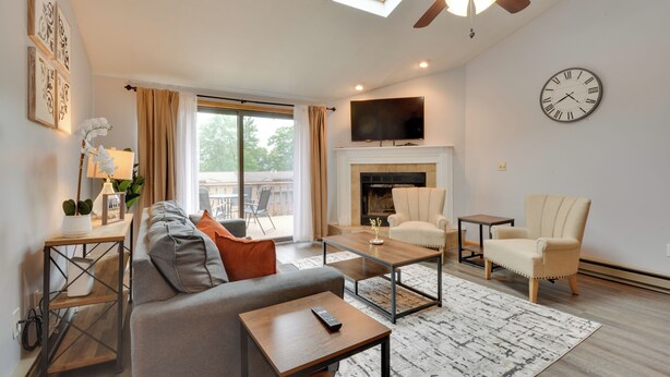 A modern living room with a sofa, coffee table, armchair, fireplace, TV, and a ceiling fan. - Oakland Vacation Rental < 1 Mi to Deep Creek Lake! (Oakland)
