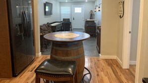 A kitchen with a wooden table, a black leather stool, and a large wooden barrel. - Excellent location right across the street from the Expo Center! – Sleeps 8 (Tulsa)