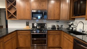 A kitchen with wooden cabinets, a stainless steel stove, a microwave, and a sink. - Excellent location right across the street from the Expo Center! – Sleeps 8 (Tulsa)