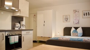 A compact kitchen with a coffee maker, oven, and cabinets.