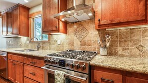 A kitchen with wooden cabinets, a stainless steel stove, and a tiled backsplash. - Spacious Retreat at Dollar Point (Tahoe City)