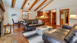 A spacious living room with a leather sofa, a coffee table, and a dining area with a table and chairs. A kitchen is visible in the background. - Spacious Retreat at Dollar Point (Tahoe City)