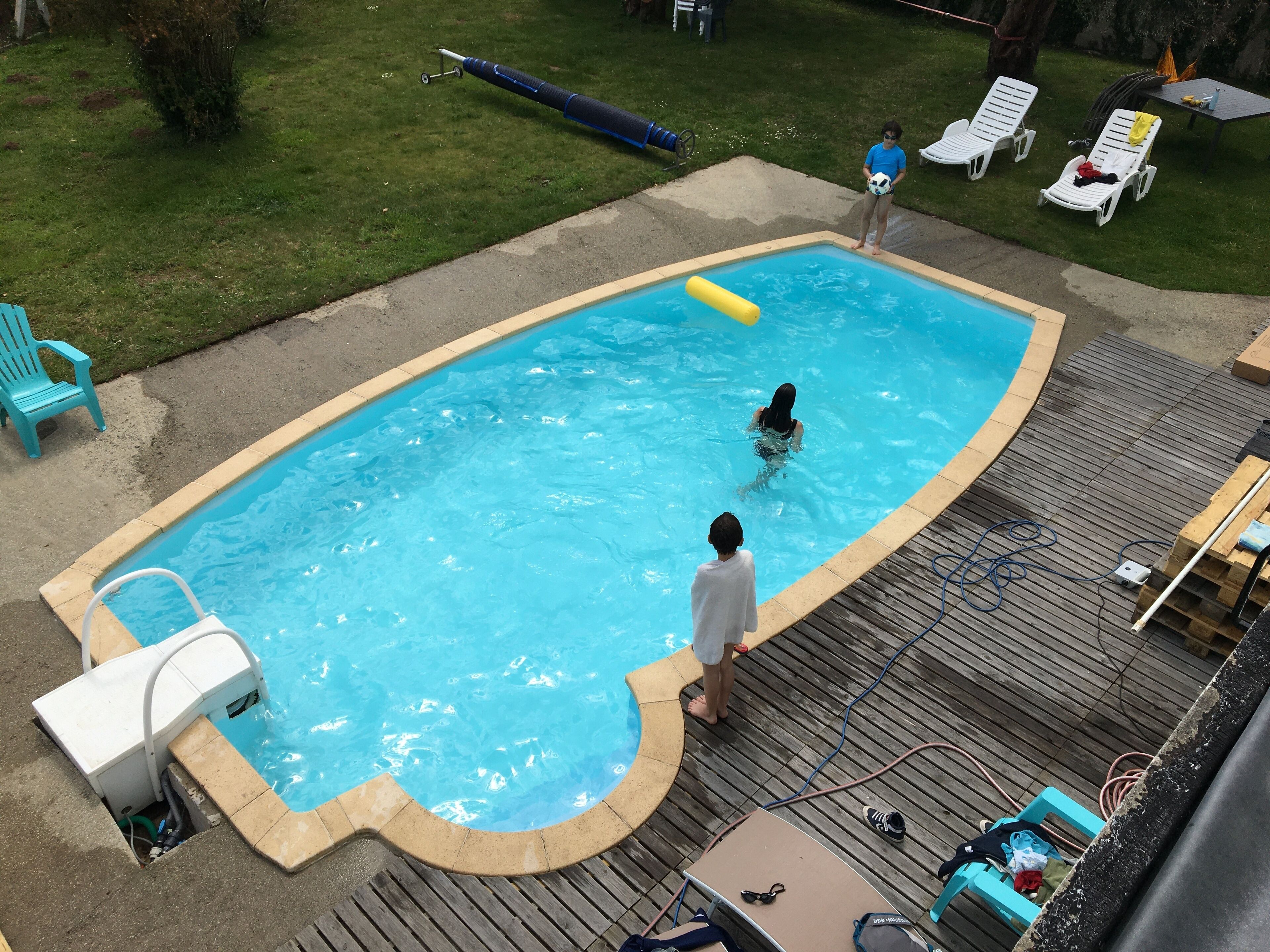 A rectangular swimming pool with a wooden deck surrounding it.