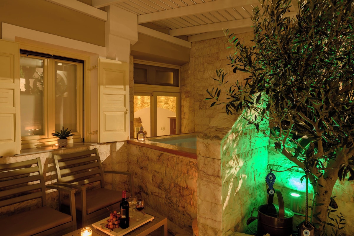 A cozy indoor seating area with a stone wall, a small pool, and a green-lit tree sculpture.