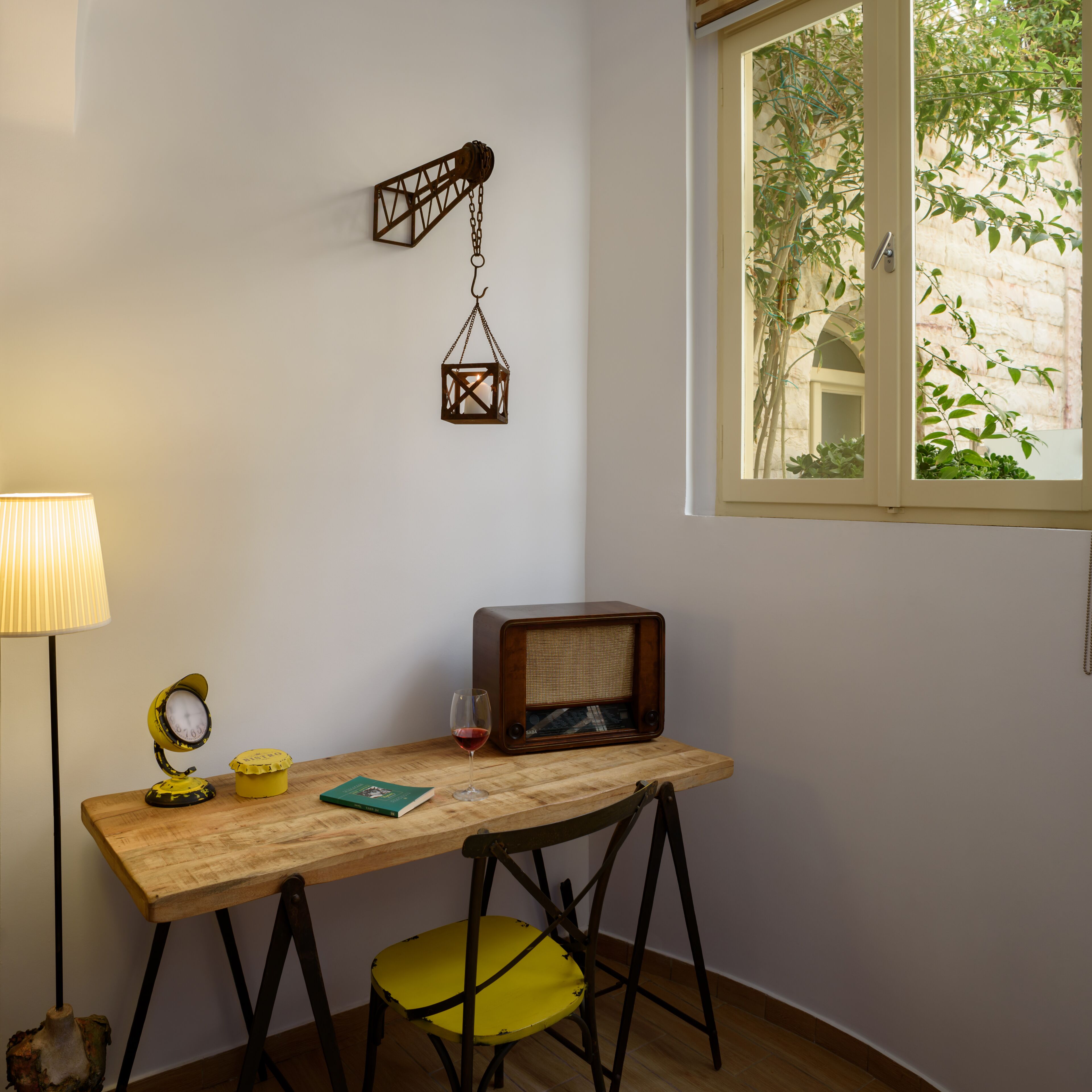 Ein Holztisch mit einem Stuhl, einer Lampe, einem Radio und einer hängenden Laterne.