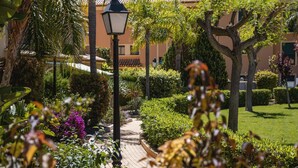 Un sentier de jardin bordé d’un lampadaire, entouré d’une végétation luxuriante et de plantes en fleurs.