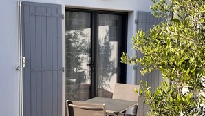 Un patio con tavolo e sedie, una porta scorrevole in vetro e un piccolo albero.